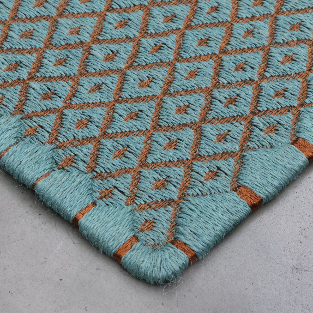 RHOMBUS WEAVE RUG IN LIGHT TURQUOISE FIQUE FIBER AND COPPER